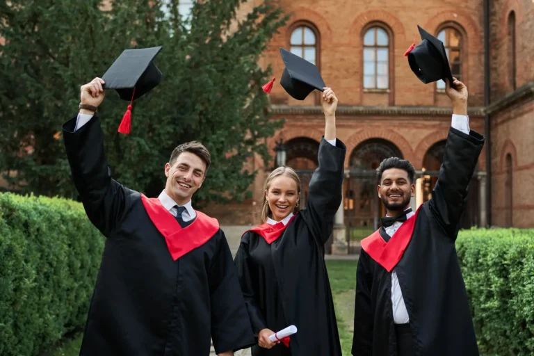 multinational-graduates-male-female-celebrating-graduation-university-campus-removing-their-graduation-hats-smiling-camera